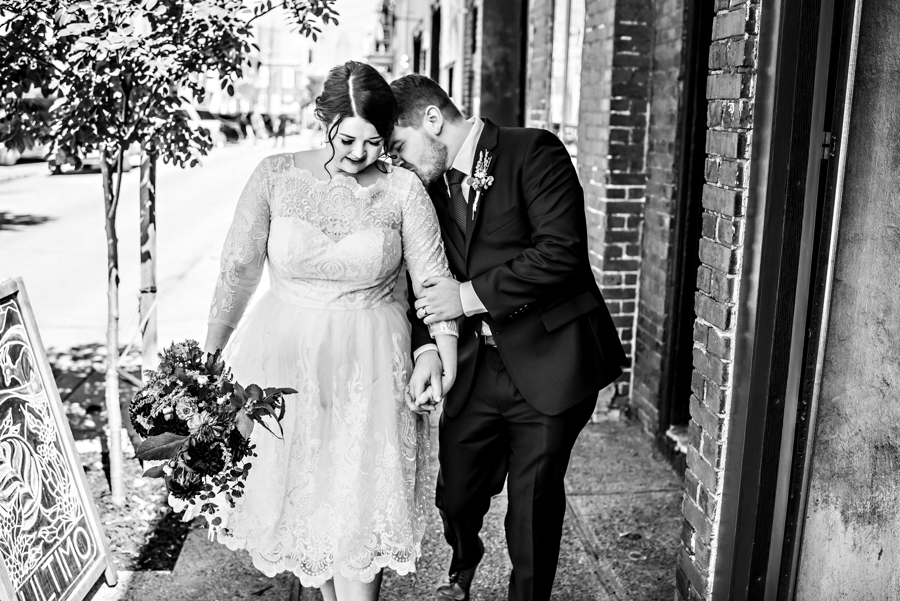 The groom kisses his new wife's shoulder as they leave the ceremony.